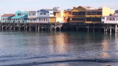 Yığınlar, sütunlar ve sütunlar üzerindeki renkli ahşap evler, okyanus suyu, tarihi Eski Balıkçılar İskelesi, Monterey Körfezi veya limanı, Kaliforniya kıyısı ABD. Turist sahili gezinti alanı, sahil şeridi..