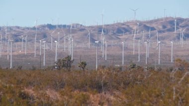 Dönen yel değirmenleri türbini, rüzgar çiftliği veya elektrik santrali alternatif yeşil yenilenebilir enerji jeneratörleri, Kaliforniya 'daki sanayi bölgesi, Mojave Çölü, Tehachapi, ABD. Rüzgâr çiftliğinde elektrik üretimi.