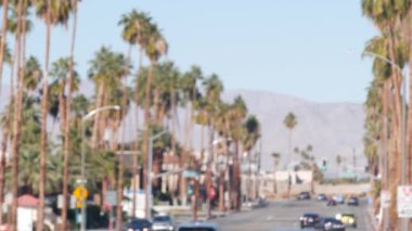Odaklanamayan palmiye ağaçları, güneşli Palm Springs şehir trafiği, Los Angeles, California, ABD yakınlarındaki tatil beldesi. Dağlık vadide iklim çölleri vahası, yaz gezisi atmosferi. Araba sürüyor..