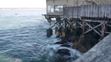 Kaliforniya, Monterey 'deki rıhtım ahşap kaldırımda. Okyanus suları ve Cannery Row caddesindeki körfez akvaryumu kıyısındaki kazık, sütun ya da sütunlarda gezinti güvertesi. Turistik tatil beldesi.