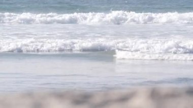 Büyük mavi okyanus dalgaları Kaliforniya Pasifik Sahili, ABD 'ye çarpıyor. Deniz suyu köpüğü ve beyaz kum. Yaz kıyı estetiği. Sörf atmosferi, Los Angeles yakınlarında deniz manzarası. Kusursuz döngülü görüntü grafiği.