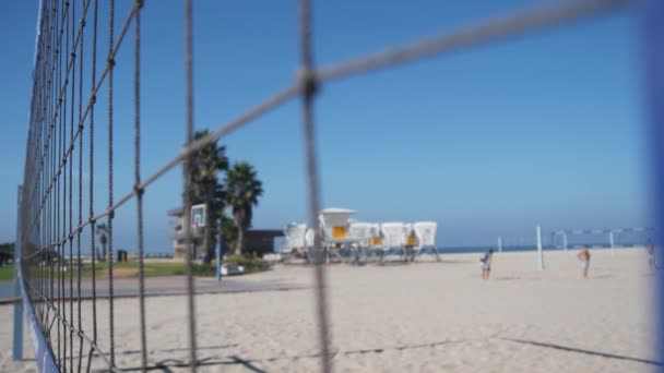 人们在海滩上打排球 美国加利福尼亚海岸的救生员小屋 棕榈树和室外运动场 游乐场或沙滩海岸的庭院 任务海滩上有网和球的娱乐游戏 — 图库视频影像