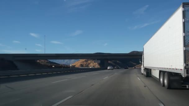カリフォルニア州の高速道路 貨物輸送のトラックや半トレーラー 高速道路の白いコンテナ運搬やトラック 商業輸送物流 バンの運搬 運転する車 — ストック動画