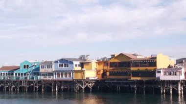 Yığınlar, sütunlar ve sütunlar üzerindeki renkli ahşap evler, okyanus suyu, tarihi Eski Balıkçılar İskelesi, Monterey Körfezi veya limanı, Kaliforniya kıyısı ABD. Turist sahili gezinti alanı, sahil şeridi..