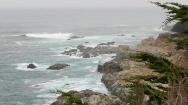Kayalık okyanus kıyısı, sisli sisli hava. Deniz dalgaları sahile çarpıyor. Kaliforniya manzarası, Big Sur doğa, ABD. Pasifik kıyısı karayolu uçurumdan ya da sarp kayalıklardan manzaralı.