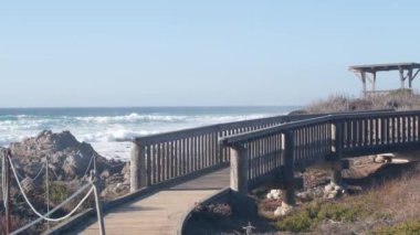 Dalgalar kayalık kayalık plajı, Monterey sahilini, Kaliforniya okyanus kıyılarını vuruyor. 17 millik sürüş doğası. Deniz suyu sıçraması, deniz manzarası. Pebble plajındaki tahta kaldırım, turistik çevre yolu..