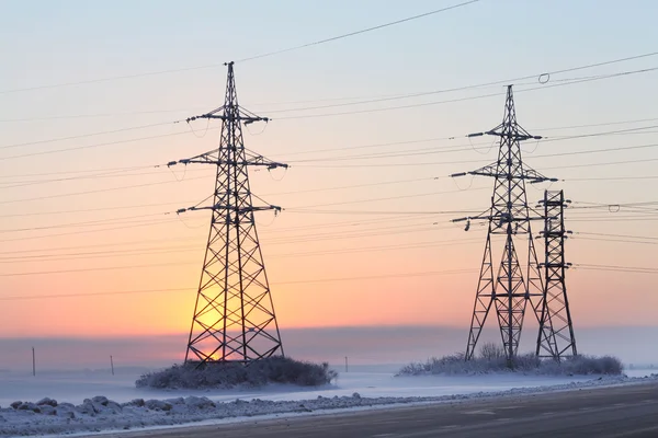 Fios e postes de alta tensão no campo de inverno — Fotografia de Stock