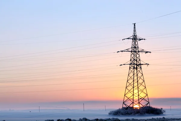 Высоковольтные провода и столбы в зимнем поле — стоковое фото