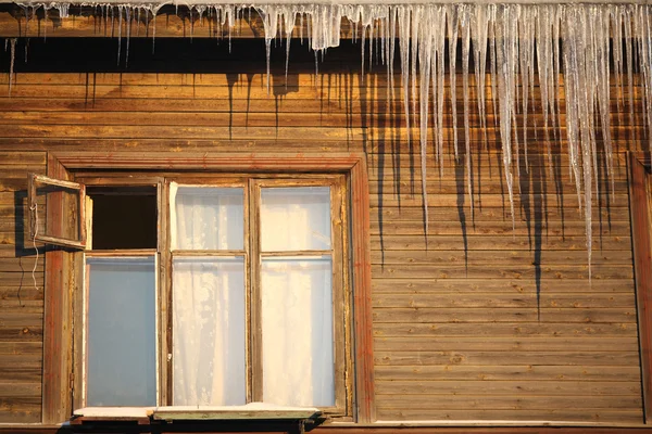 Carámbanos en el techo de una casa de madera con ventanas —  Fotos de Stock