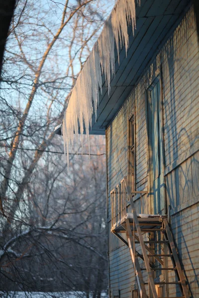 Glaçons sur le toit d'une maison en bois avec fenêtres — Photo