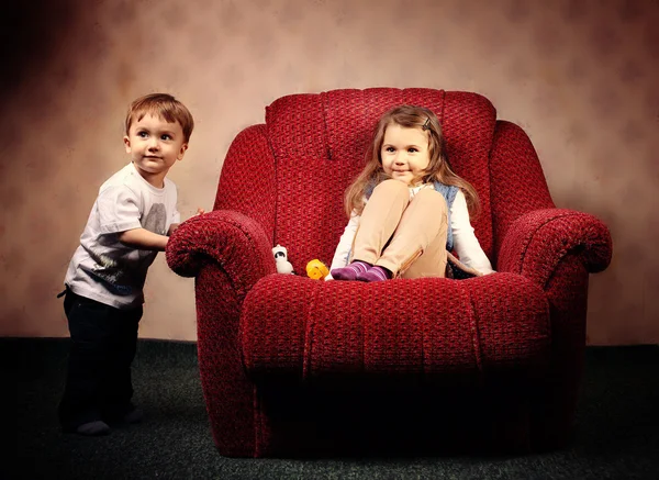 Verplaatsen naar een ander appartement, de kinderen verplaatsen een grote rode stoel — Stockfoto