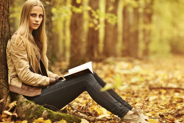 Ung vacker flicka med en bok i höst skogen — Stockfoto