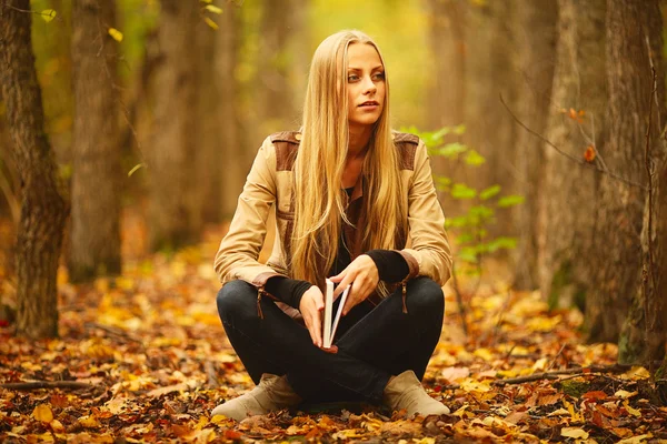 Menina com um livro na floresta de outono — Fotografia de Stock