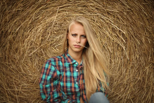 Junge schöne Blondine im Heu draußen — Stockfoto