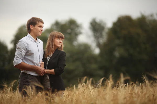 Joven y mujer caminando en un campo de trigo — Foto de Stock