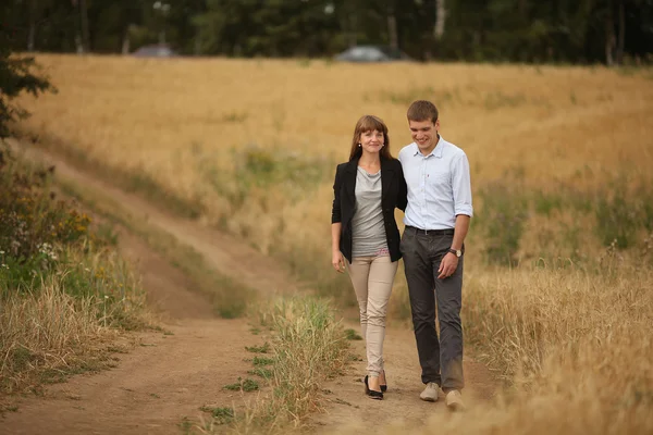 Young man and woman walking in a field of wheat — Stock Photo, Image