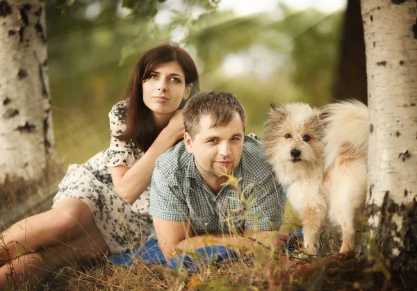 Jovem homem e mulher ao ar livre brincando com um pequeno cão — Fotografia de Stock