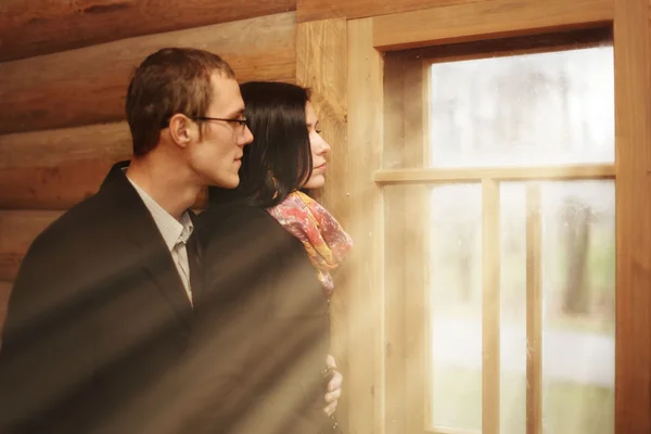 Jovem homem de família e uma mulher em uma casa de madeira rústica — Fotografia de Stock