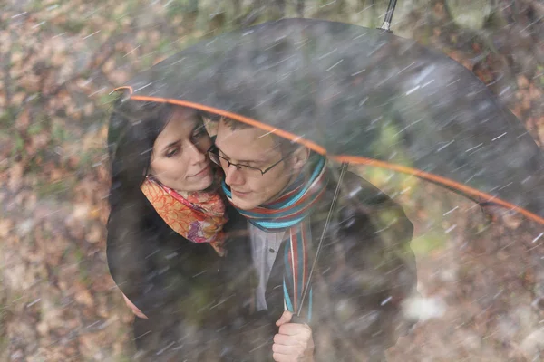 Giovane coppia sotto un ombrello nella foresta autunnale — Foto Stock