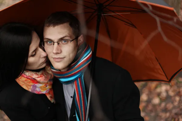 Jovem casal sob um guarda-chuva na floresta de outono — Fotografia de Stock