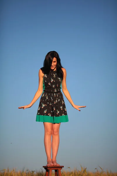 Beautiful girl with a stool in the field — Stock Photo, Image