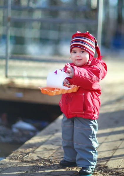 Little cheerful girl 2-3 years, runs the boats in the spring puddle — Stock Photo, Image