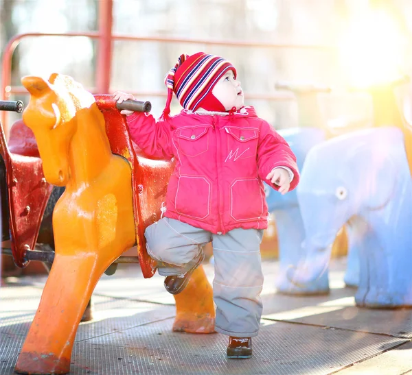 Liten lystig jente i 2-3 år, leker på karusellen – stockfoto