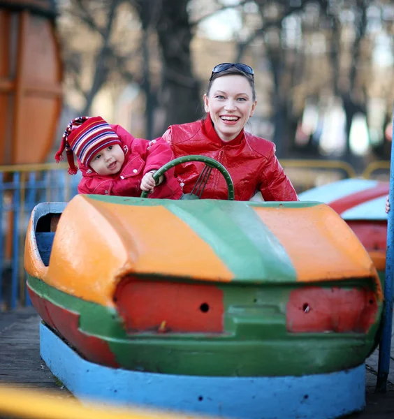 Mutter und kleine Tochter fahren auf dem Karussell, im kleinen Auto — Stockfoto