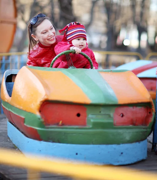 Moeder en jonge dochter rijden op de carrousel, in kleine auto — Stockfoto