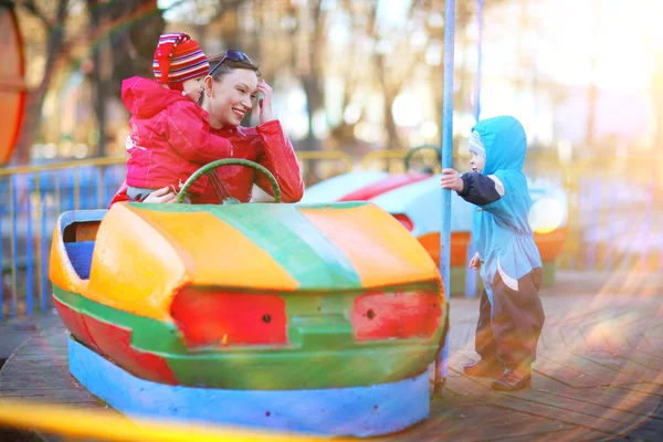 Bambini godendo di un giro in auto paraurti con la madre — Foto Stock