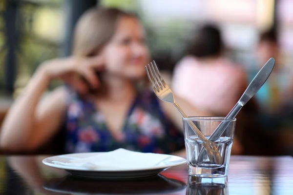 Cuchillo y tenedor en el restaurante sobre un fondo de mujer borrosa — Foto de Stock