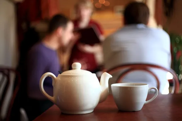 Arka plan olarak bulanık insanlarla çaydanlık portre — Stok fotoğraf