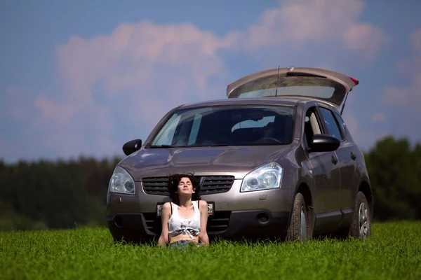 Mulher bonita sentar na frente do carro em um campo — Fotografia de Stock