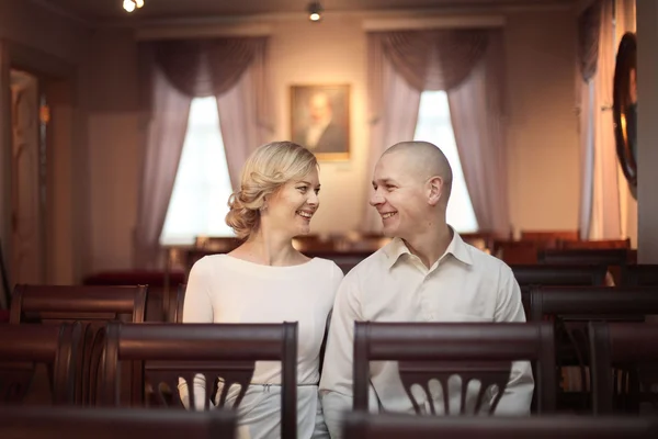 Beautiful young man and woman sitting on the chairs in the auditorium alone — Stock Photo, Image