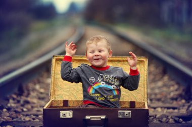 Tren yolculuğu yanında bir bavul içinde oturan çocuk