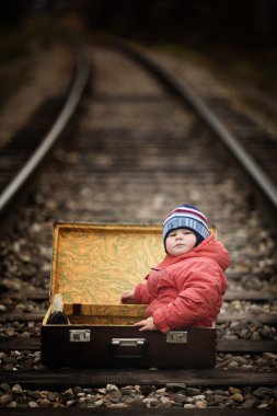 Tren yolculuğu yanında bir bavul içinde oturan çocuk