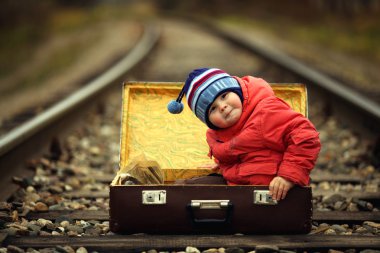 Tren yolculuğu yanında bir bavul içinde oturan çocuk