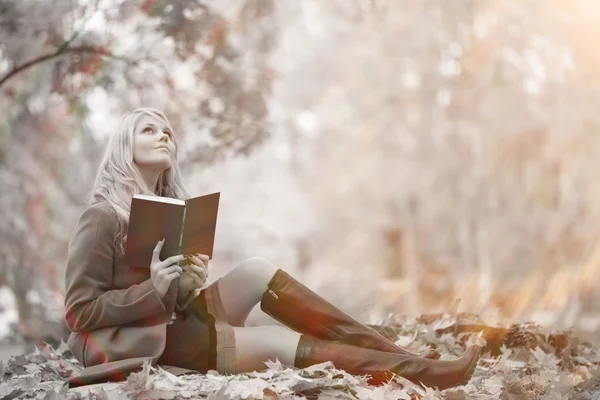 Chica leyendo un libro en el parque de otoño — Foto de Stock