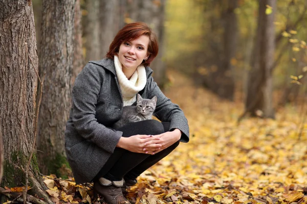 Flicka och en katt i höst park — Stockfoto