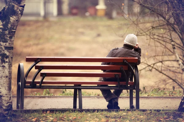 Homem solitário no banco outono — Fotografia de Stock