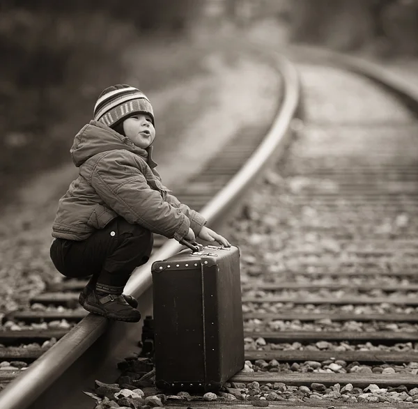 男孩坐在附近的铁路旅程的手提箱 — 图库照片