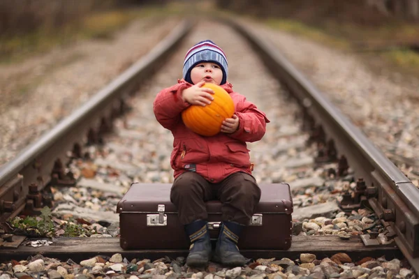 Niño sentado en una maleta cerca del viaje en tren — Foto de Stock