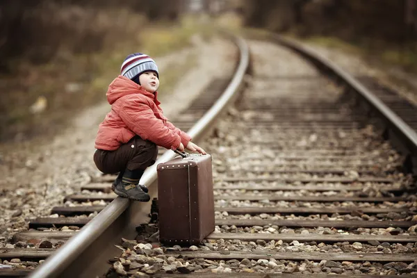 Boy sitting in a suitcase near the railway journey — Stock Photo, Image