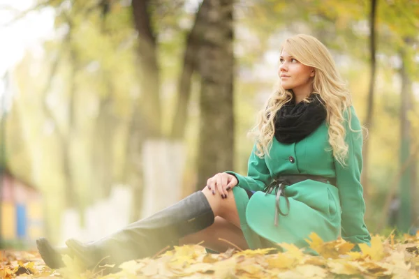 Грустная девушка сидит на желтых листьях — стоковое фото