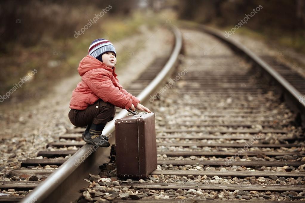Boy sitting in a suitcase near the railway journey — Stock Photo