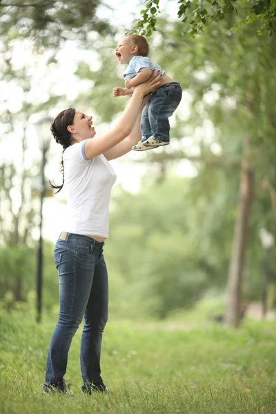 Gelukkig jonge moeder spelen met baby in het park — Stockfoto