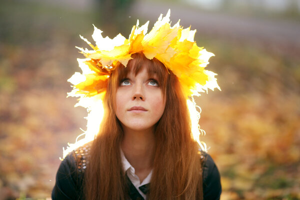 Portrait of a woman wearing maple leaves wreath in autumn park