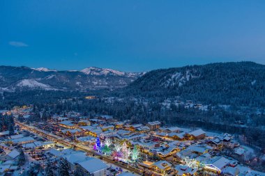 Aydınlatılmış bir Leavenworth, Washington 'un havadan görünüşü ve 2021 yılına yakın çağlayan dağlarını kaplayan kar