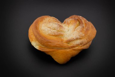 Kalp ya da plyushka Moskovskaya şeklinde siyah arka planda izole edilmiş maya çöreği. Lezzetli ve güzel bir çörek. Rusça gerçek stil