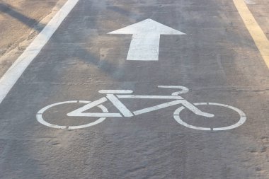 Asfaltta Bisiklet ve Ok izleri var. Bisikletçiler için kaldırım. Asfaltta beyaz yol izleri var. Bisiklet şeridi sembolü. Hareketin yönünü gösterir